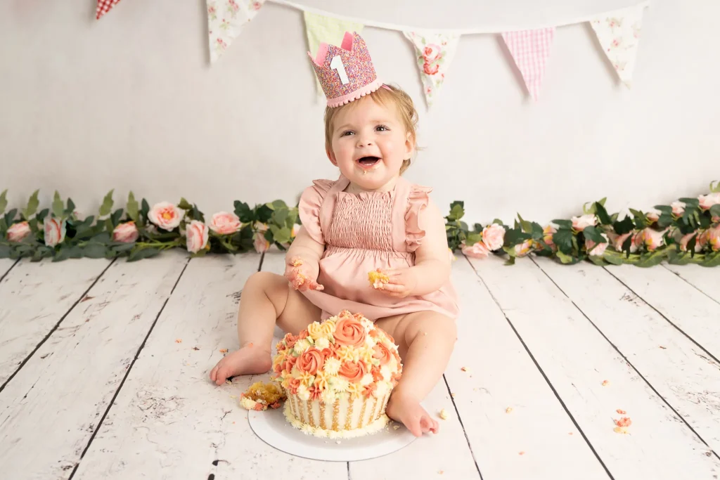 baby in a 1 crown sat with cake