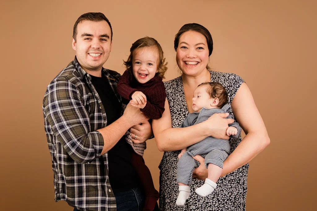 Family of four two adults two children posing for a studio photo