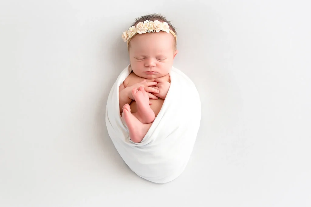 Newborn baby wrapped in white with flower headband